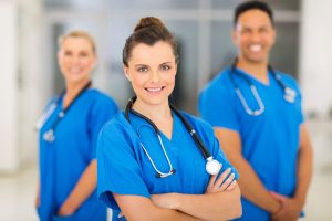 three smiling rn nurses wearing blue uniforms and stethoscopes