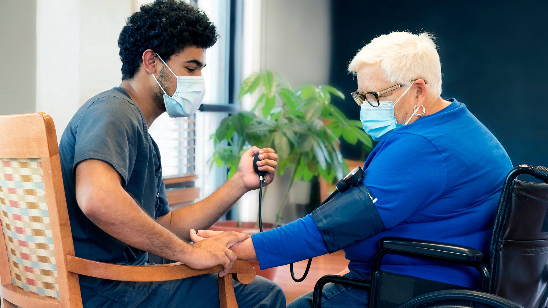 An image of a CNA taking the blood pressure of an elderly nursing home patient, highlighting the importance of CNA jobs in nursing homes.