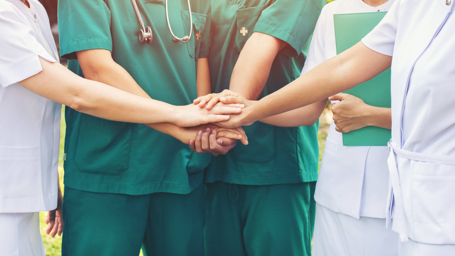 A group of five nurses stand in a circle united with their nursing license.