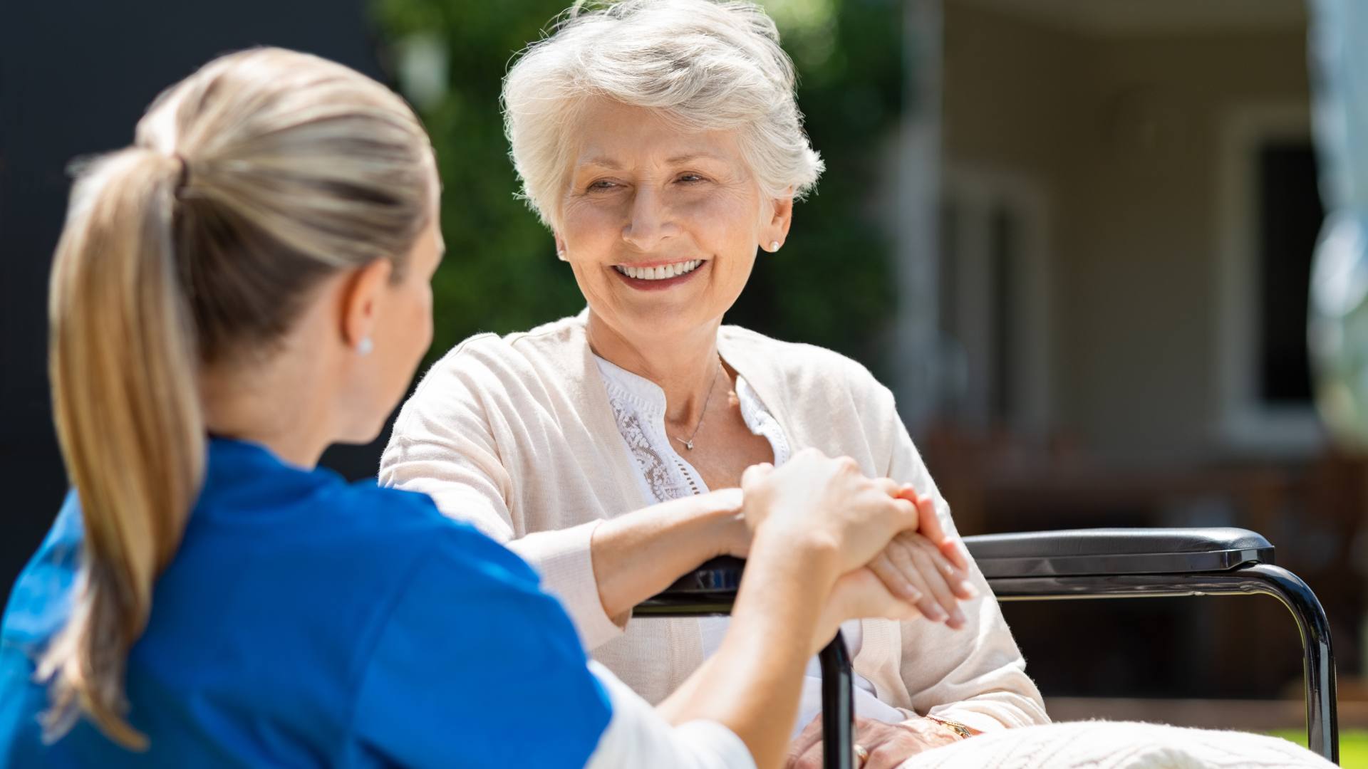 A nurse sits with a patient outside of a personal care facility.