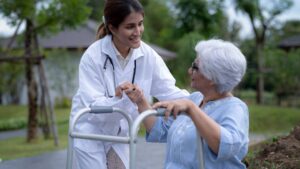 A med tech at a nursing home assists a patient outside with her walker.