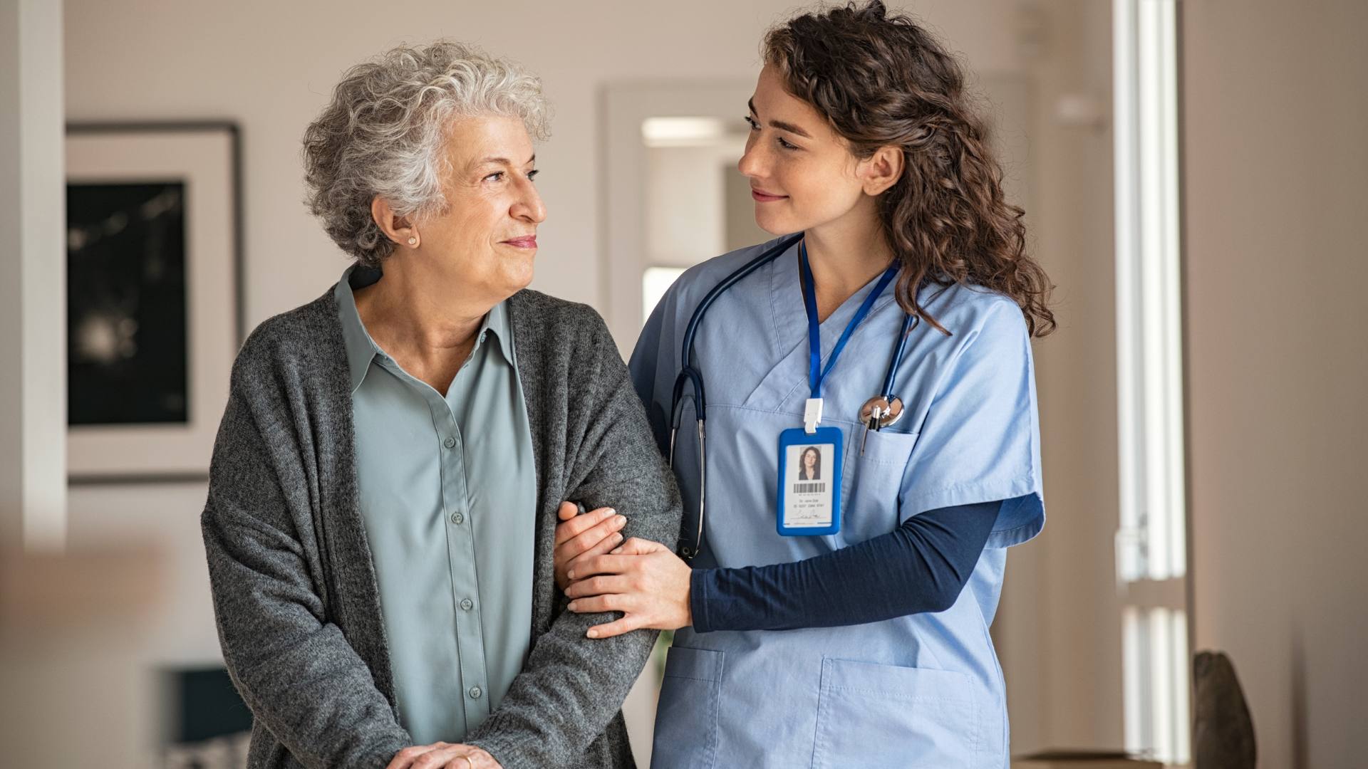 A licensed practical nurse smiles while holding the arm of a senior resident, demonstrating the role of licensed practical nurses in senior living communities.