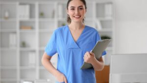 A clinical nurse specialist (CNS) wearing blue scrubs smiles at the camera.